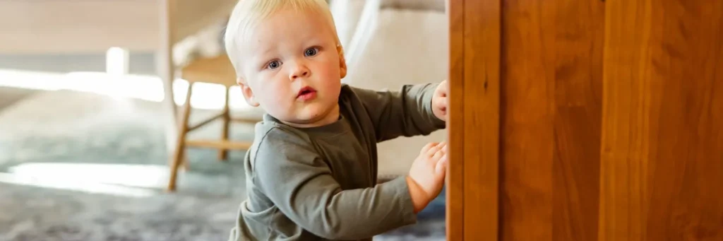 Infant playing by a bedroom chest